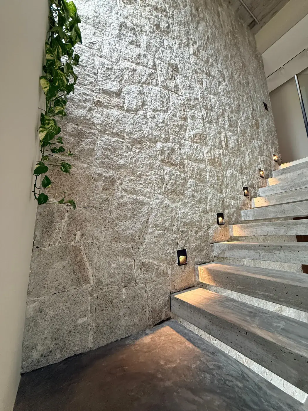 Escada com LED e parede de pedra em destaque